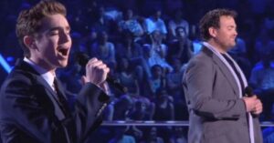 2 uomini sul palco cantano la potente canzone “You Raise Me Up”