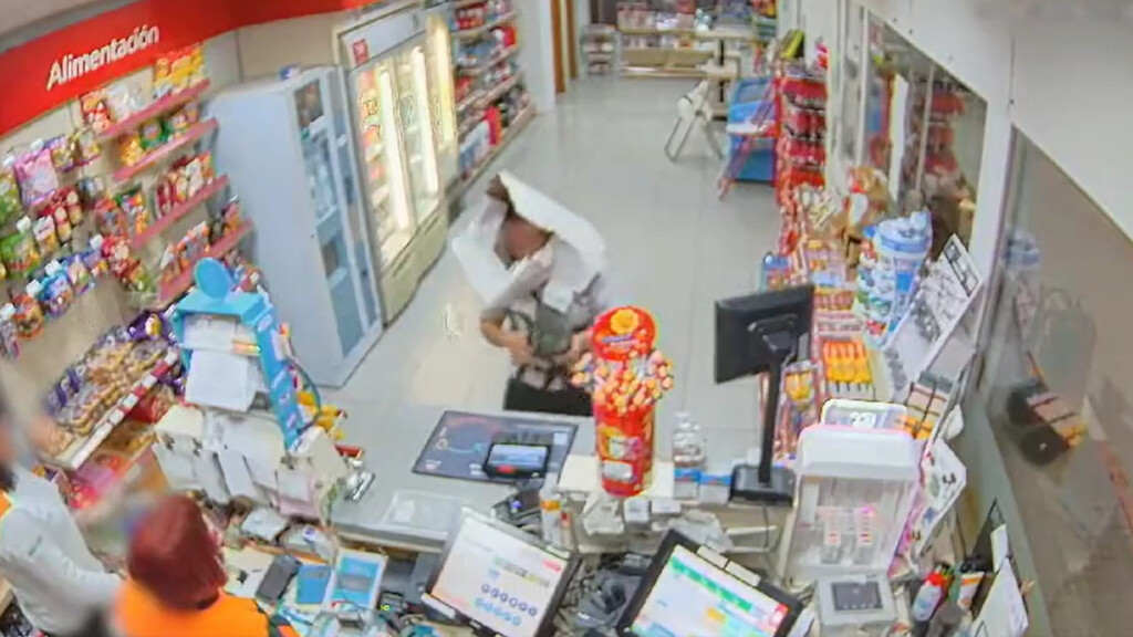 Un uomo rapina un negozio con una scatola sulla testa